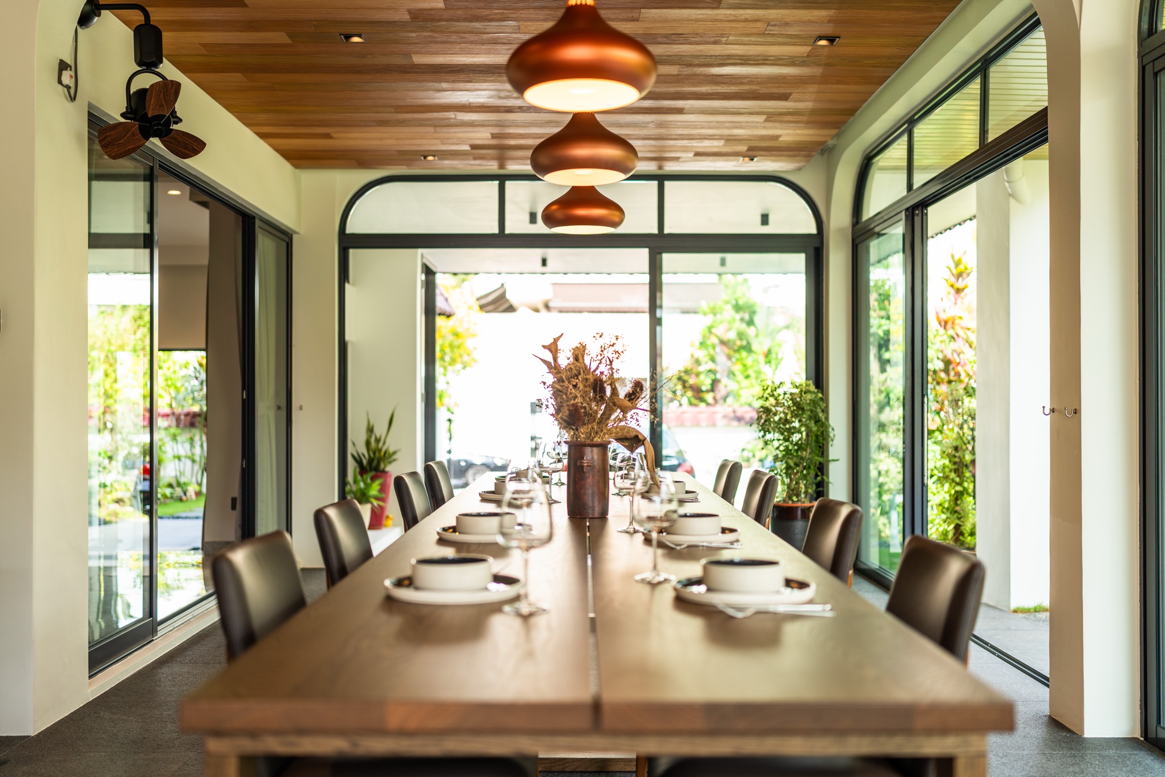 Outdoor dining pavilion with dark granite flooring set against the garden
