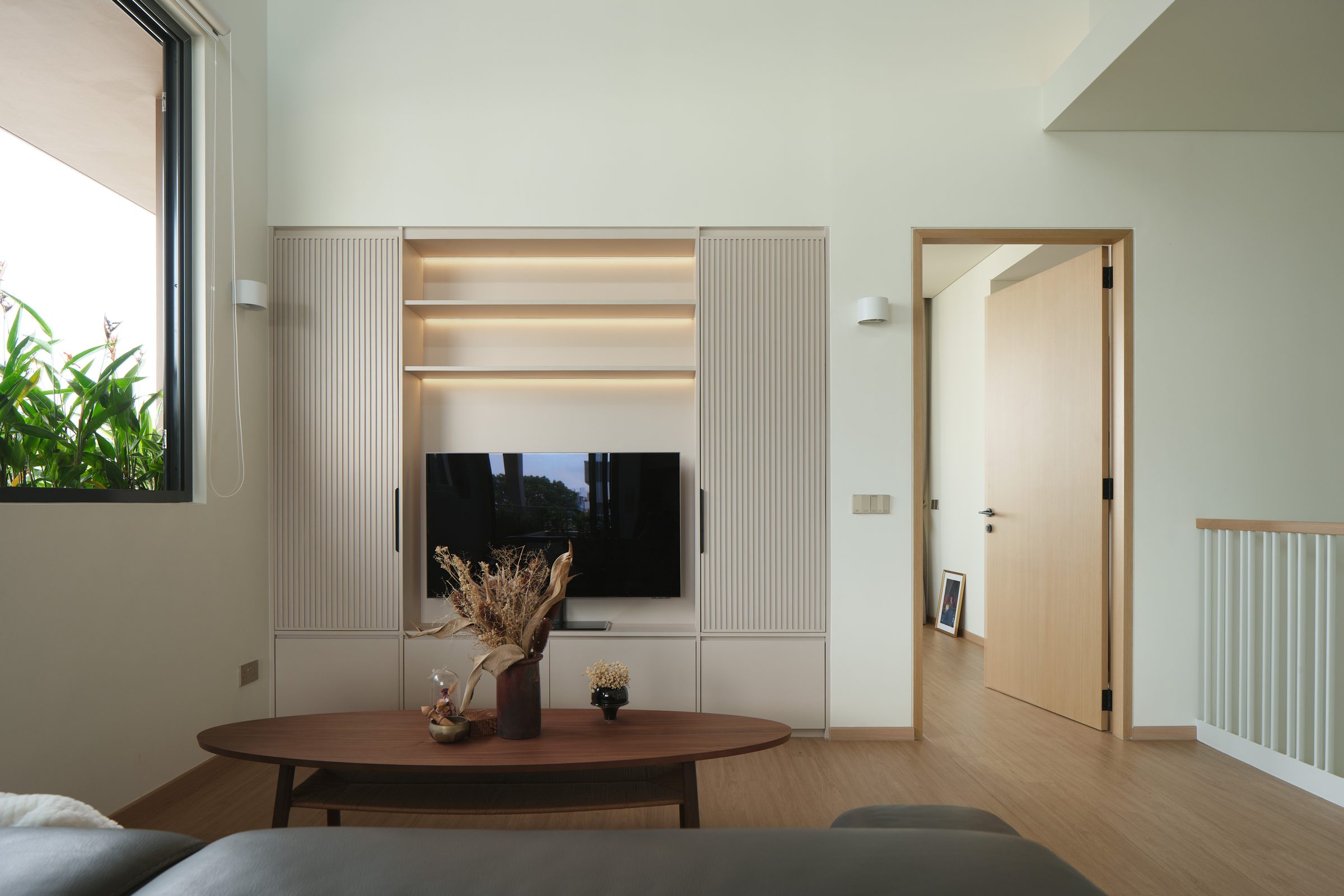 Upper-floor family lounge with fluted joinery, a walnut oval table and timber flooring beside the void balustrade