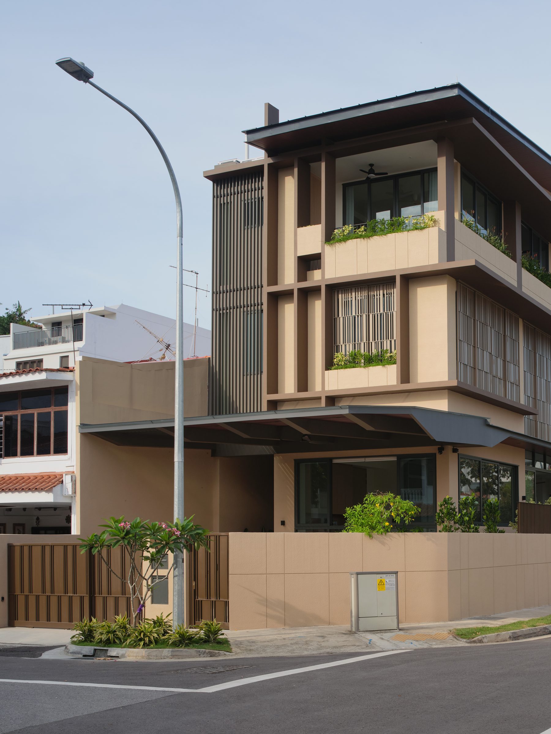 Closer corner view of the warm-toned framing, vertical fins and planter boxes stacked across the upper storeys