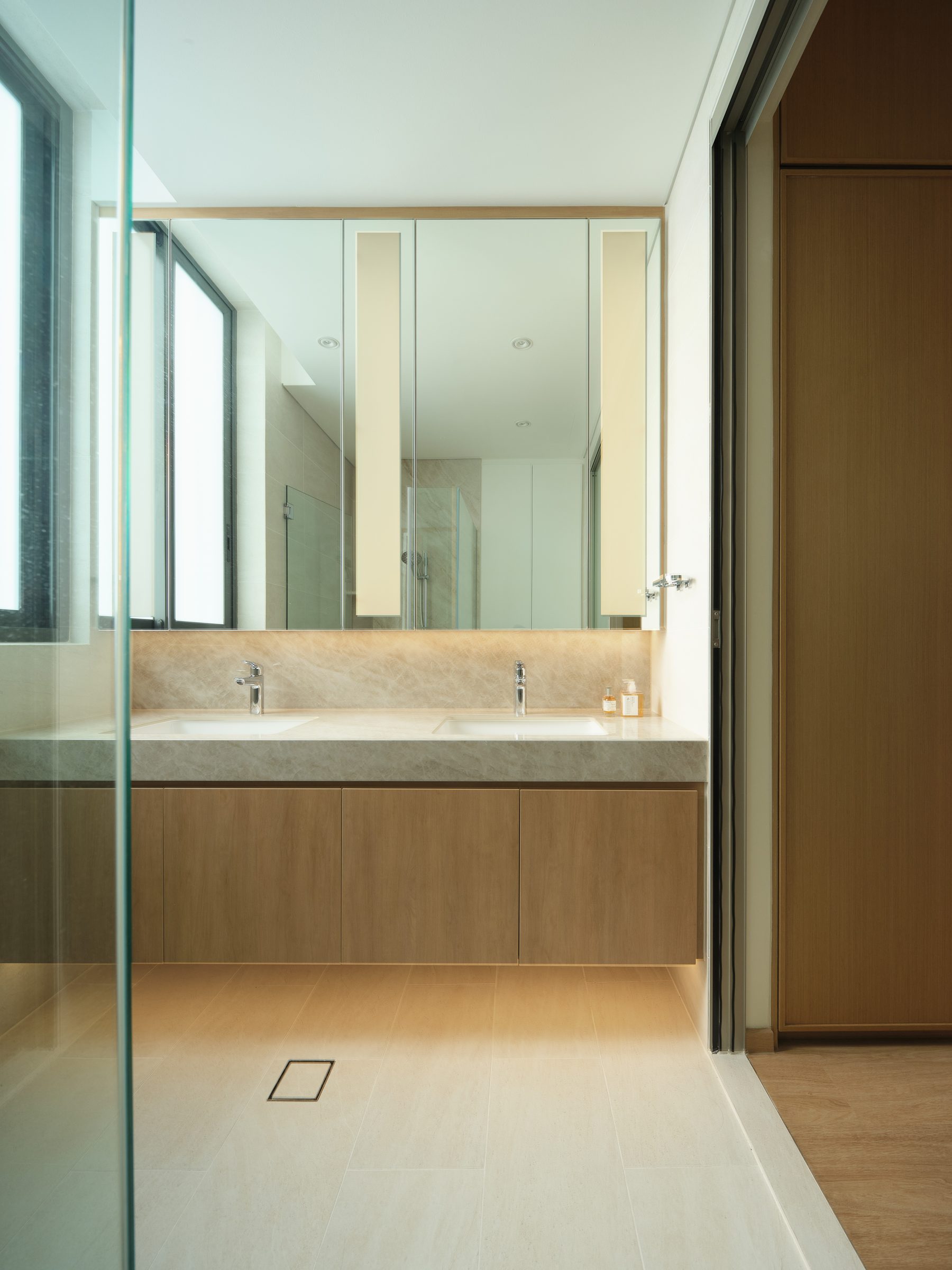 Ensuite bathroom with a twin-basin stone vanity, oak cabinetry and daylight from a full-height side window