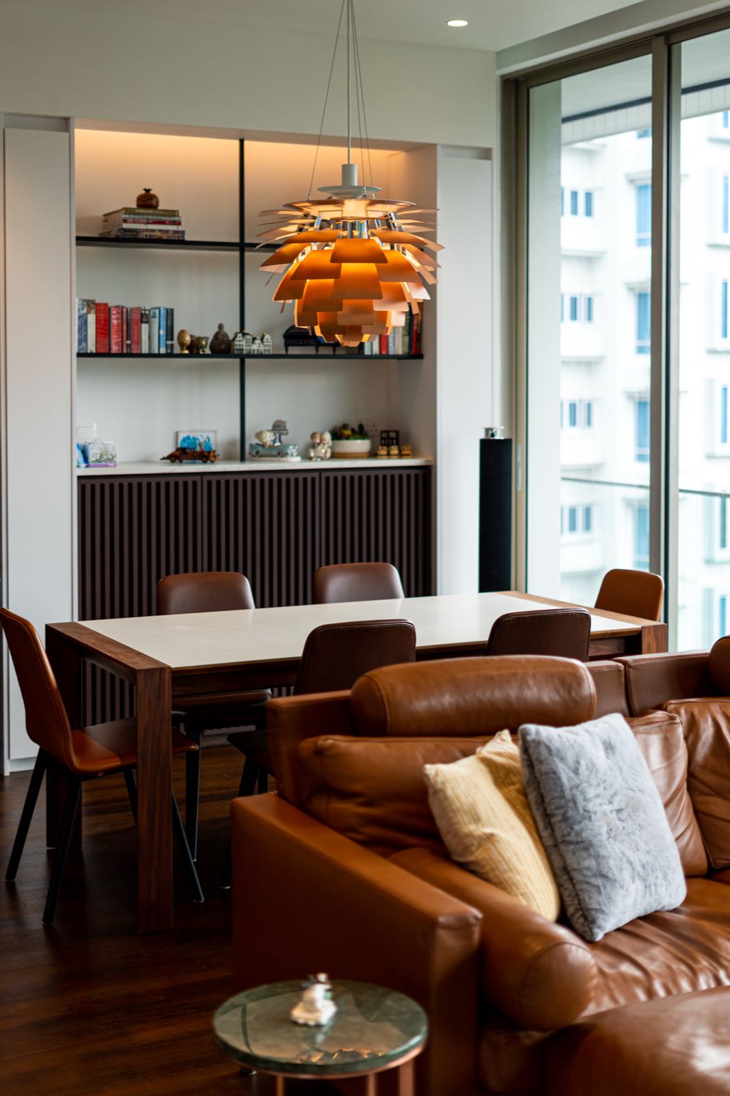 Dining and living transition with PH Artichoke pendant lamp, leather sofa, and dark timber bar
