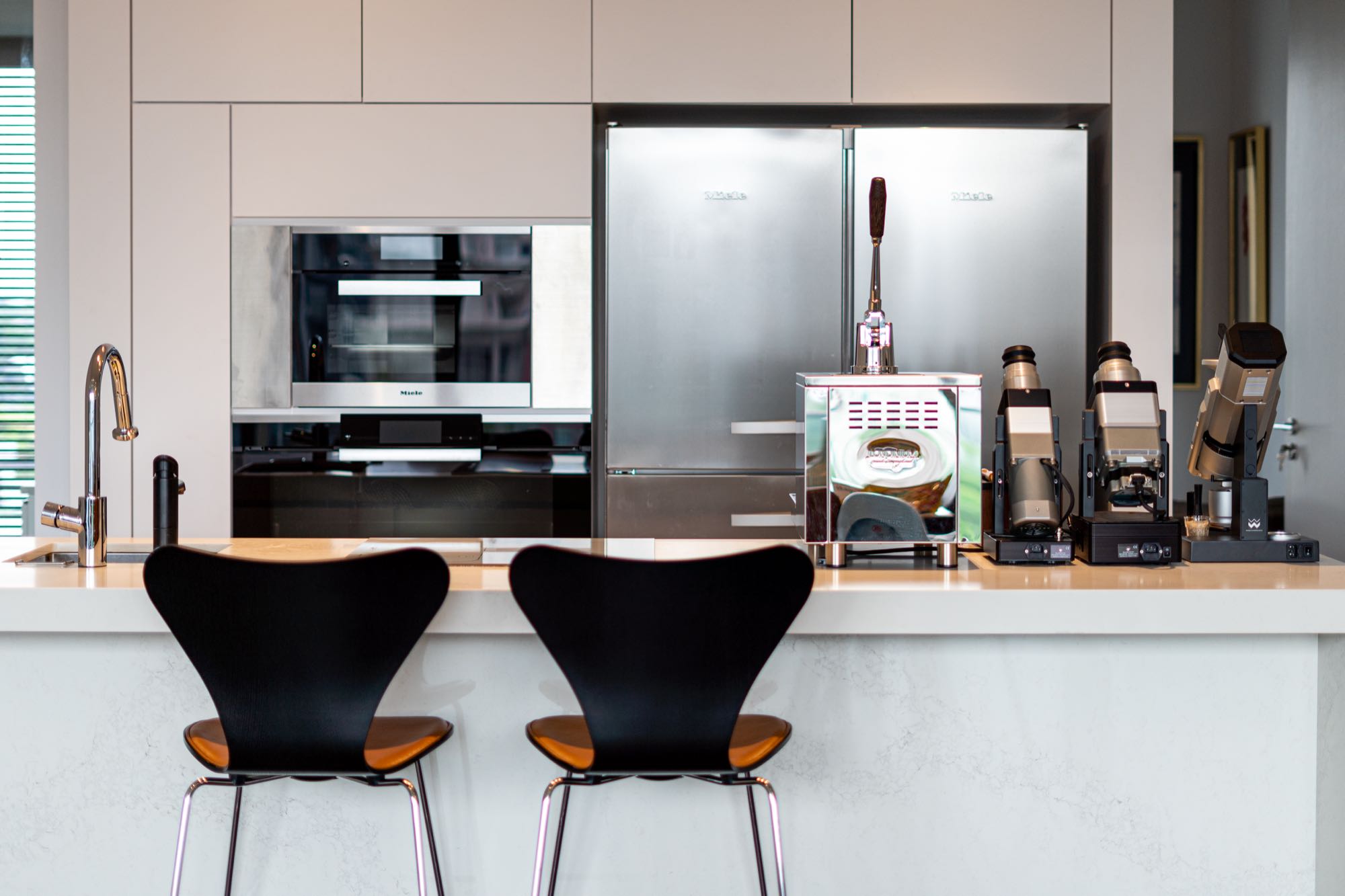 Open kitchen with Miele appliances, Arne Jacobsen Series 7 stools, and a fully-equipped espresso station