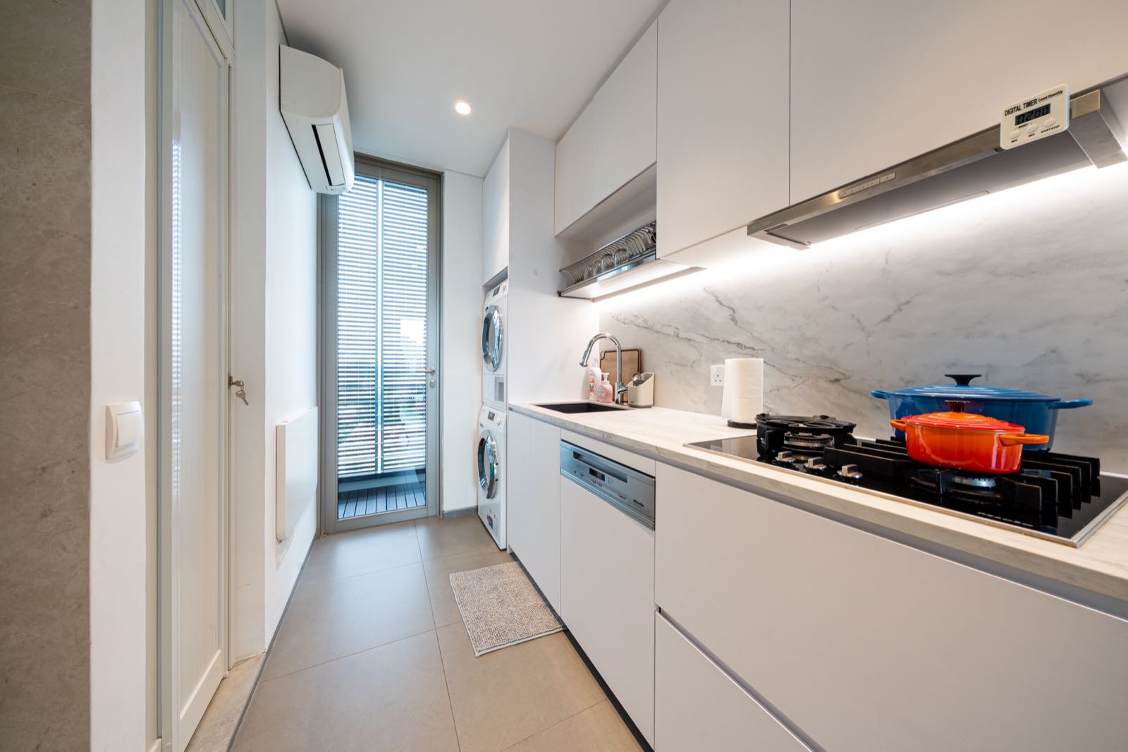 Wet kitchen with gas stove, Le Creuset pots, and white marble backsplash