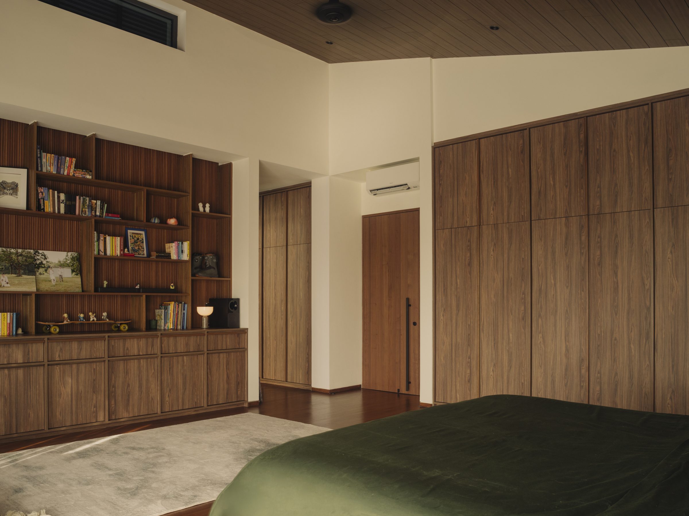 Bedroom with a run of bookshelves and joinery wall facing the bed