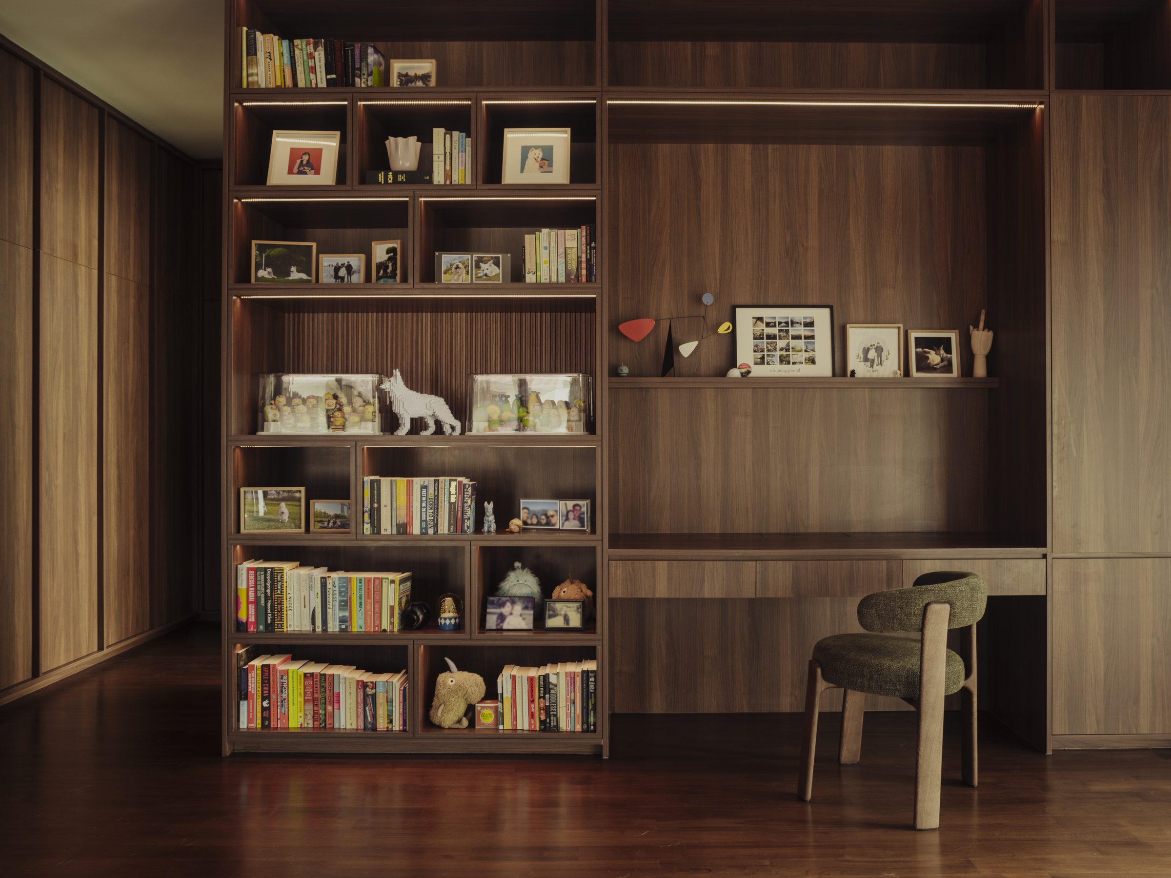 Full-height timber bookcase and desk, shelves carrying books, photographs and collected objects