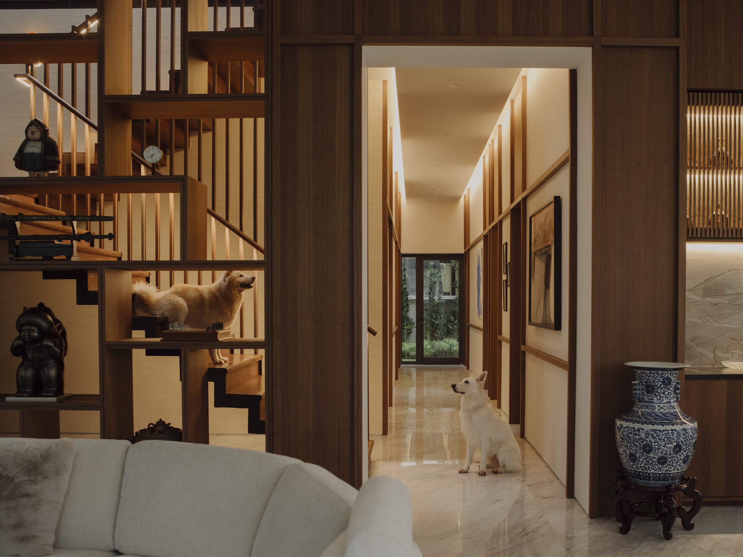 Open timber stair beside a gallery corridor, with the household dogs on the treads and in the hall
