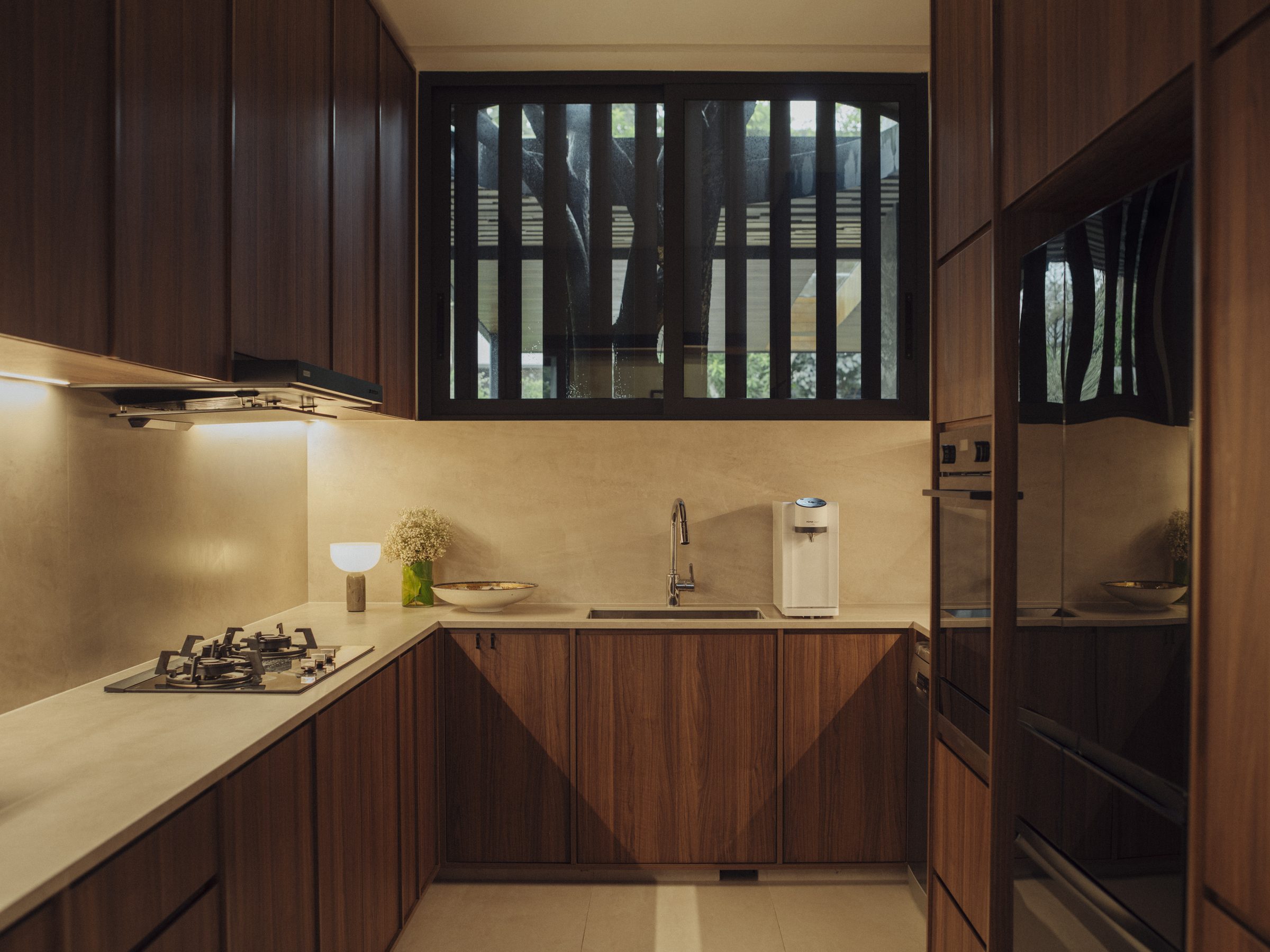 Wet kitchen in timber joinery with a stone counter and a screened window to the garden