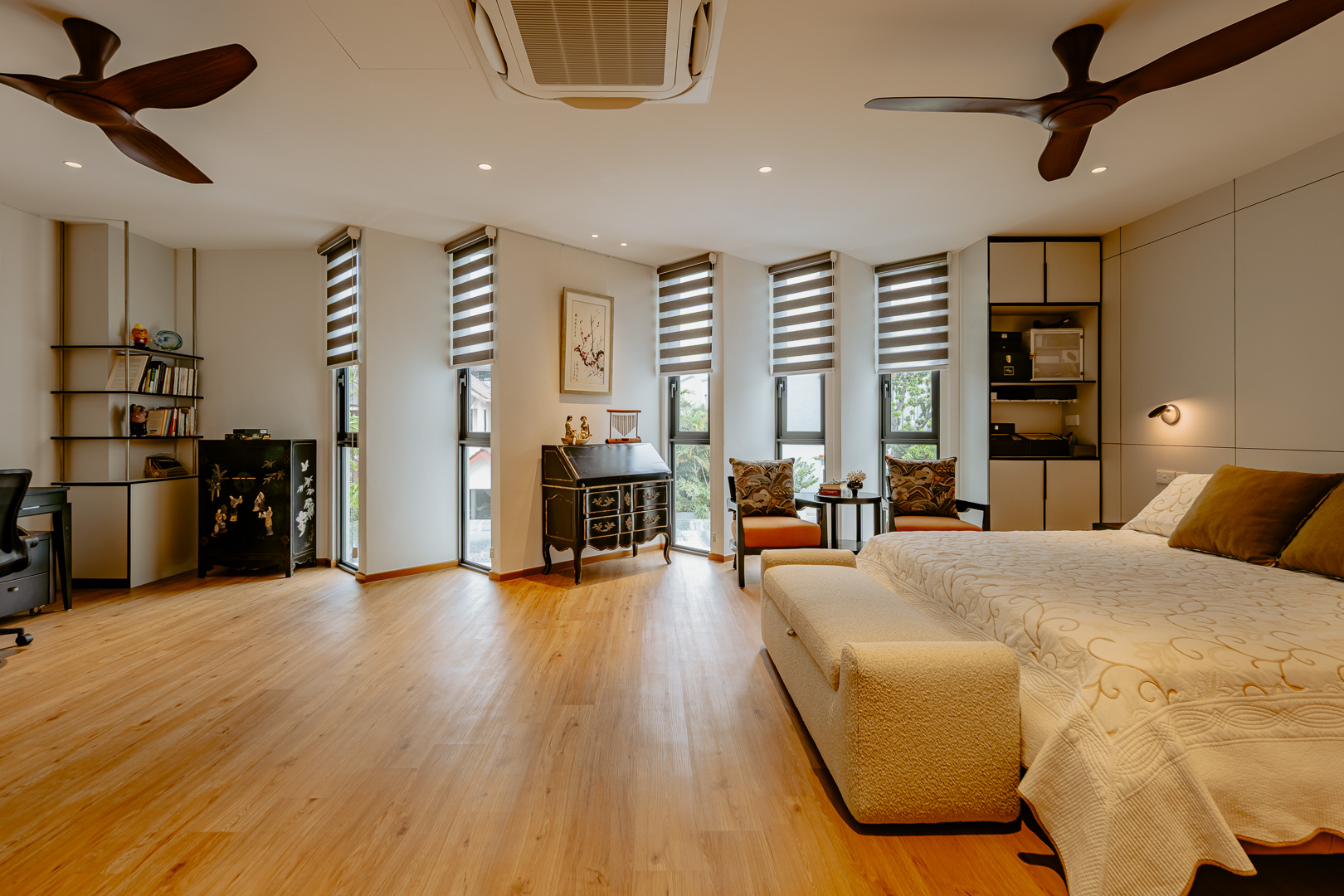 Master bedroom with timber flooring, a study nook and the family's antique lacquer cabinet set against the angled window bays