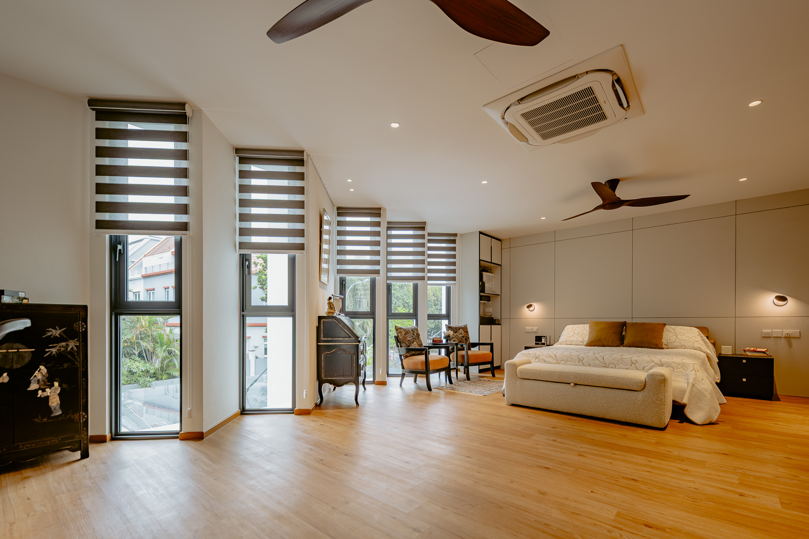 Wider view of the master bedroom showing the full run of angled glazing and the joinery wall behind the bed