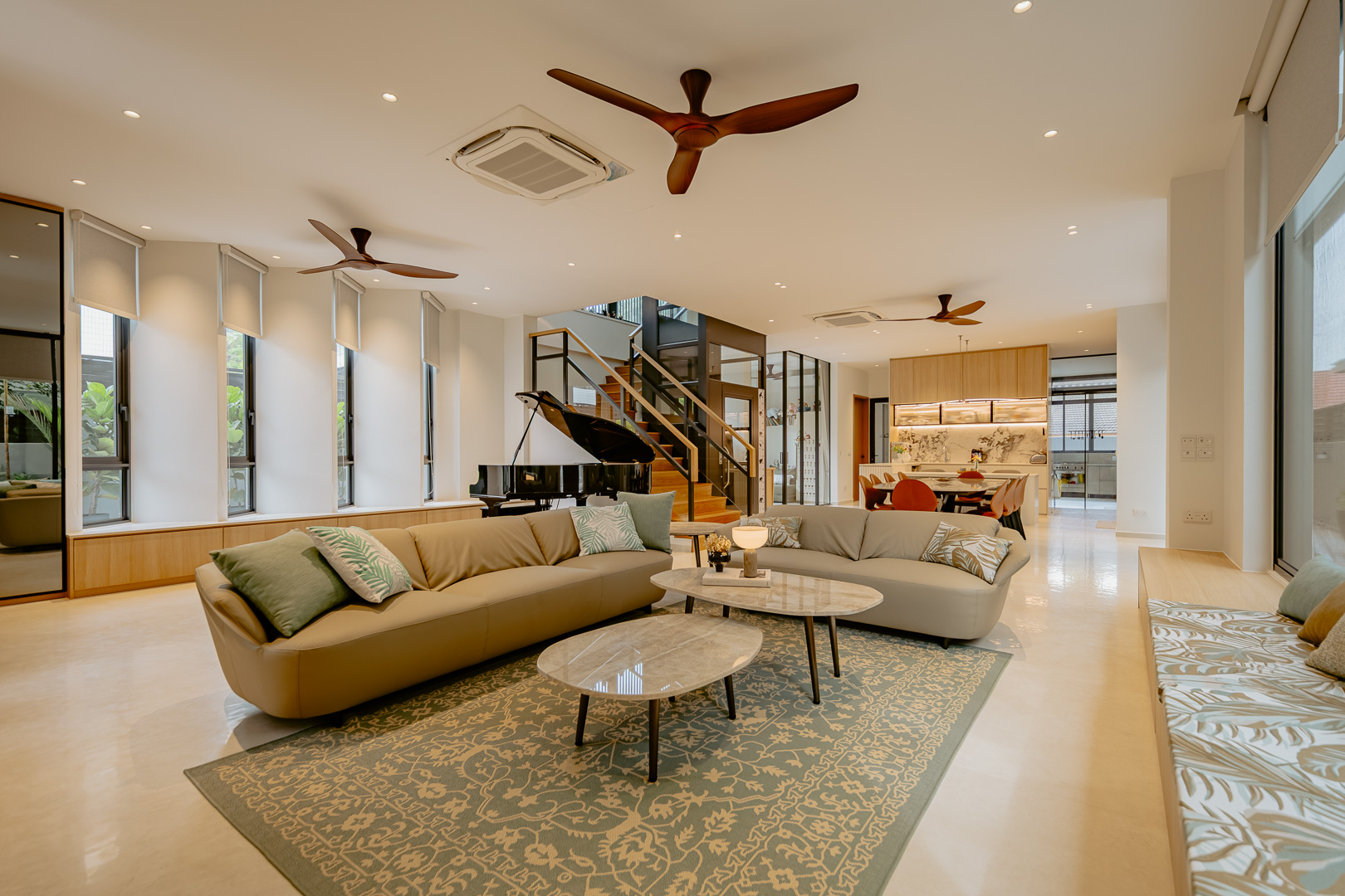 Open-plan living room with two sofas, a grand piano by the stair and the dining and kitchen area beyond
