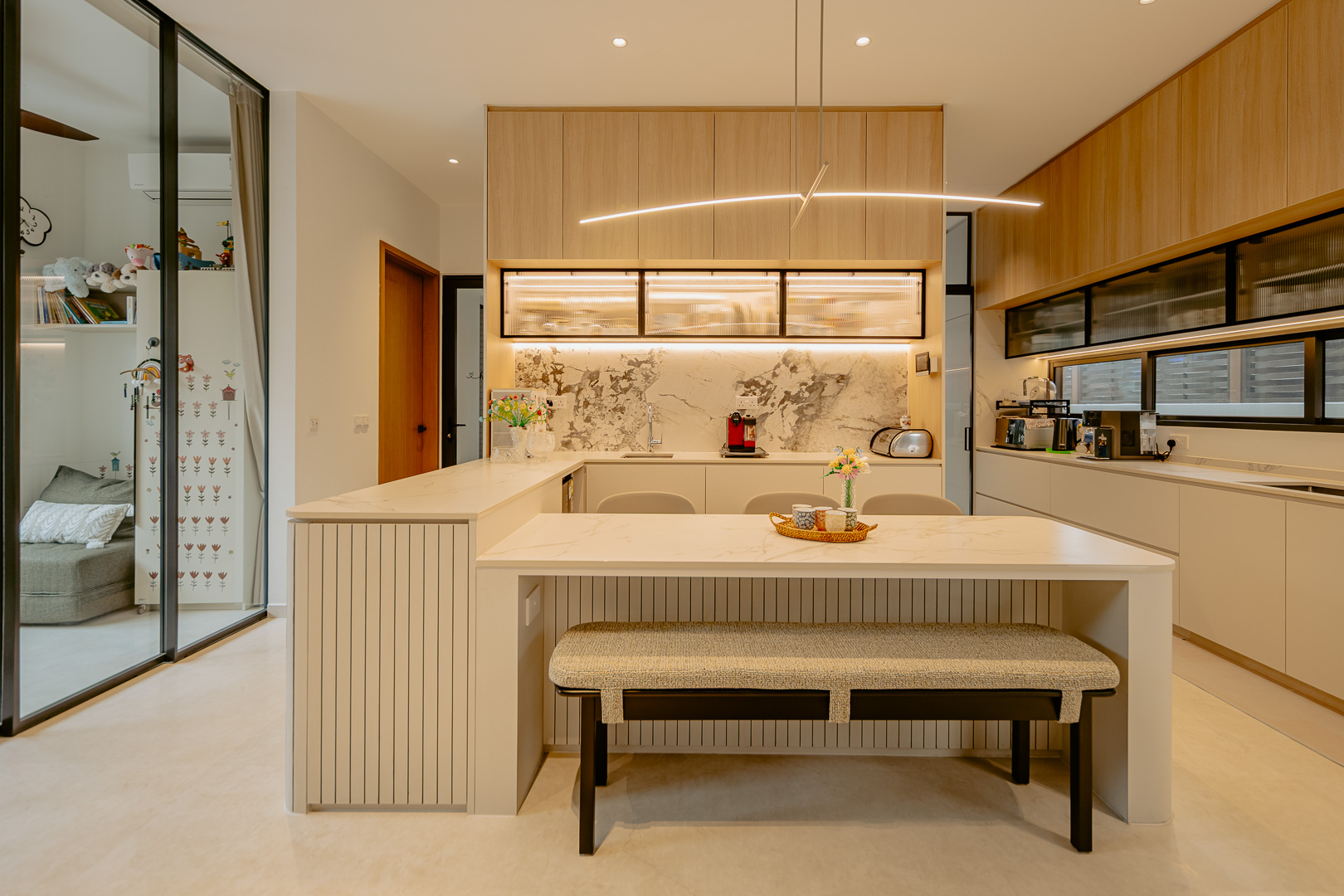 Dry kitchen with a stone island and bench seating, oak upper cabinetry and a marble-veined splashback