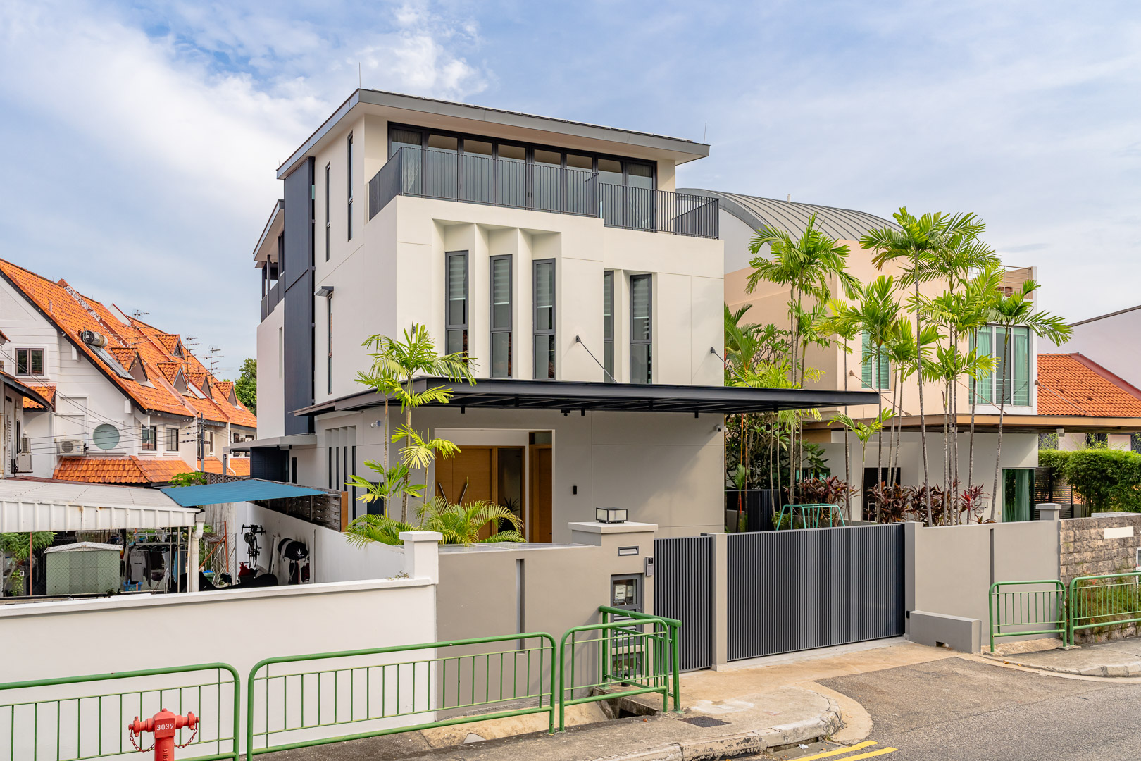 Street elevation of the three-storey house, its angled window reveals set into the cream facade above a covered entrance