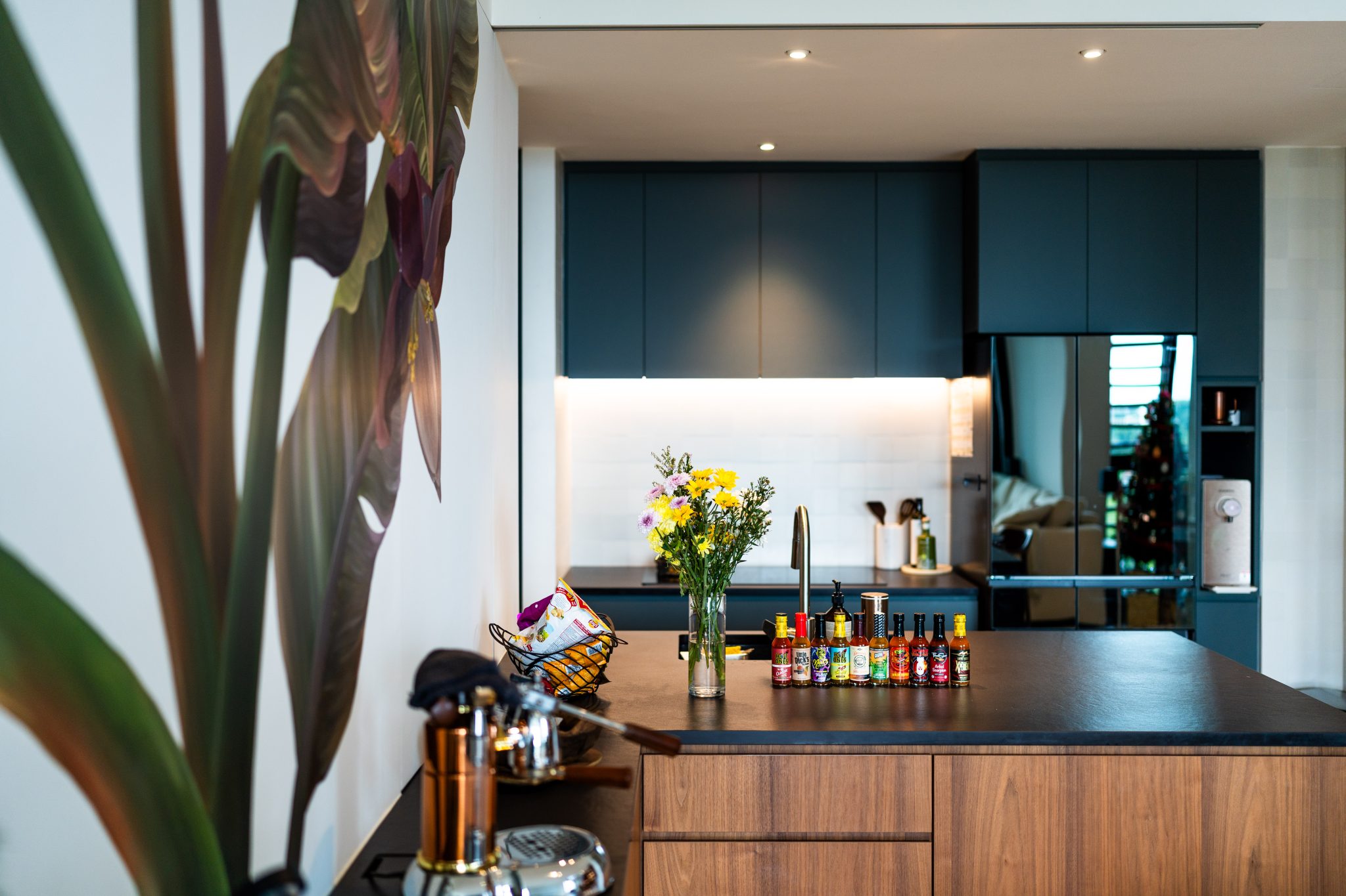 Kitchen island with a dark blue cabinetry run, seen past a wall painted with a large botanical mural