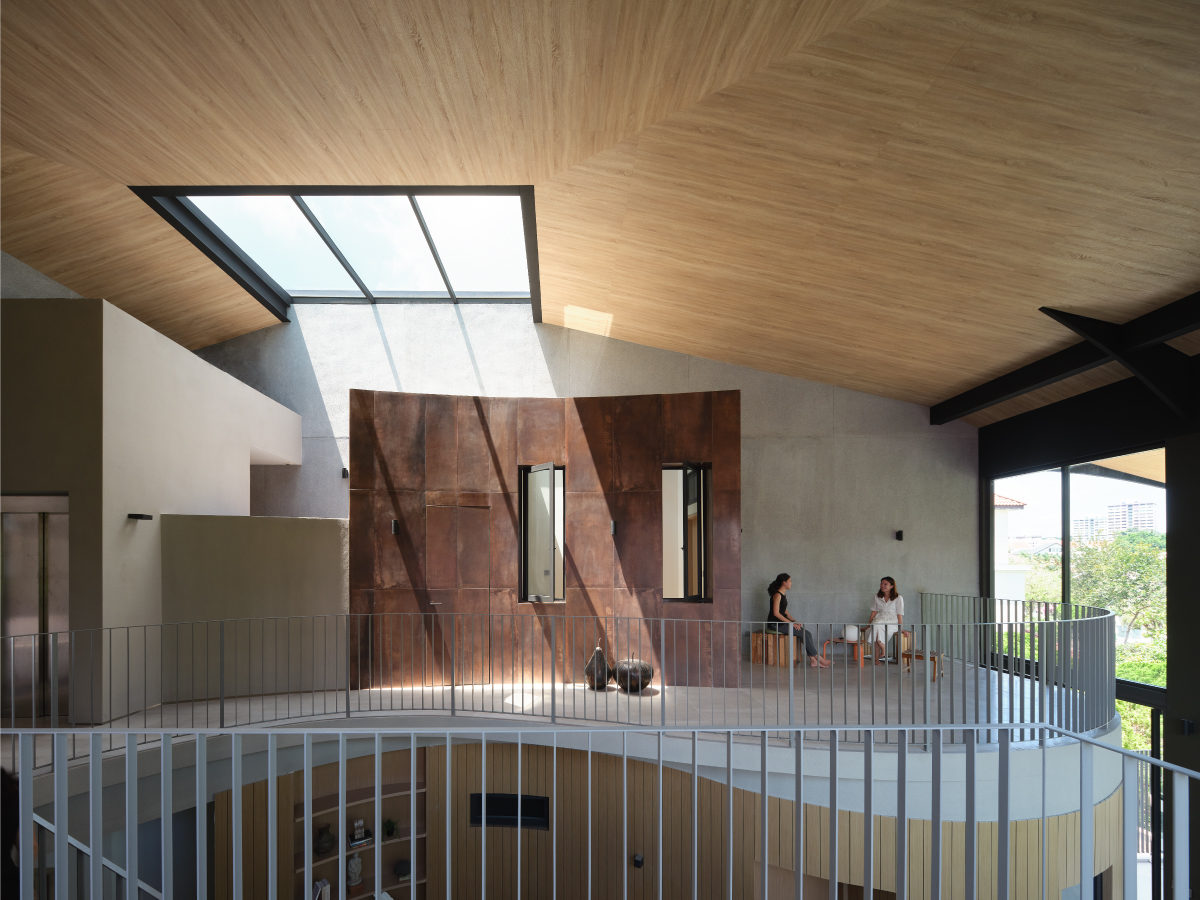 Top-floor family area under a curved timber ceiling with a skylight and an oxidised iron clad volume
