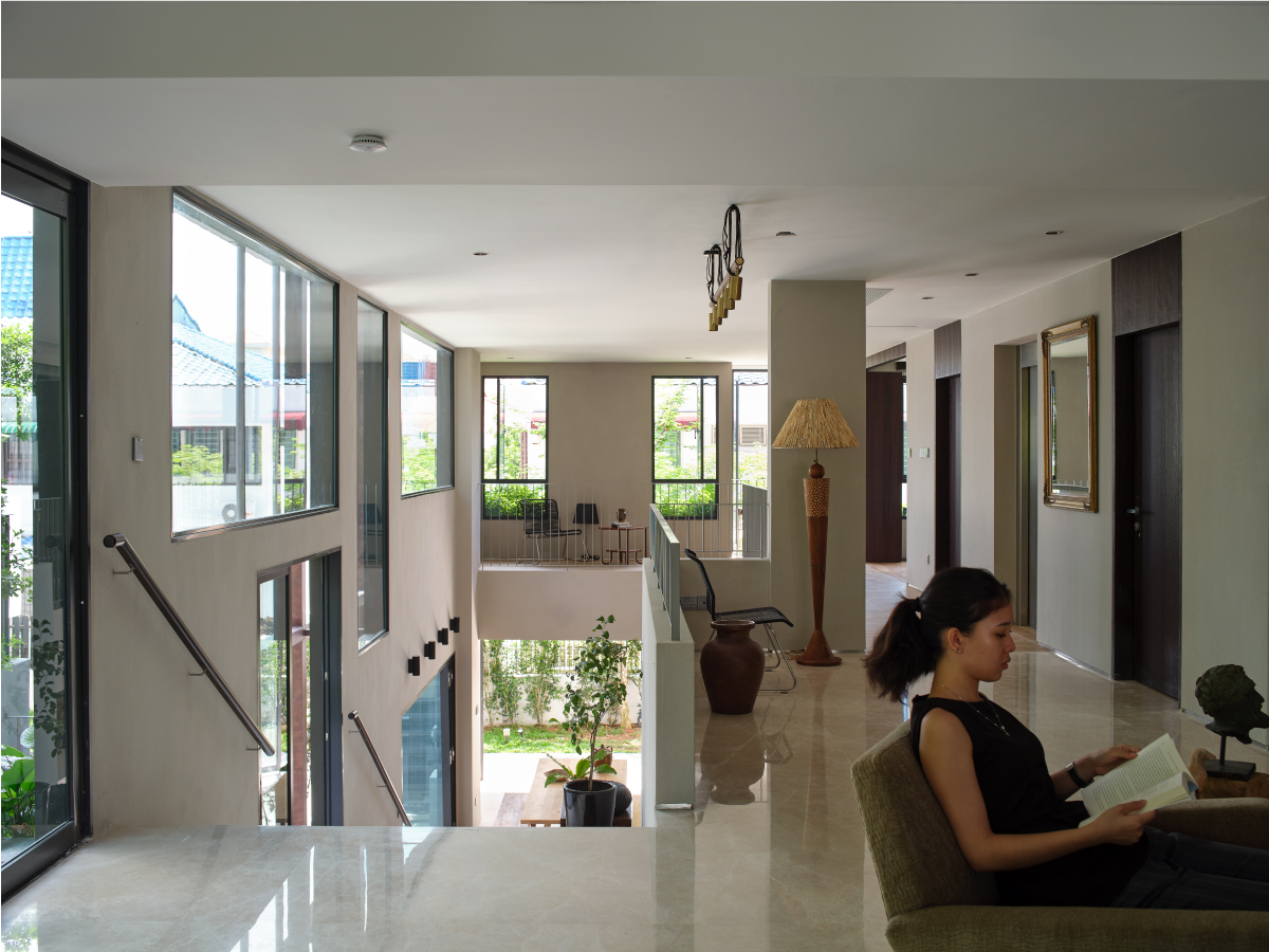 Upper landing looking across the double-volume void to tall windows framing greenery