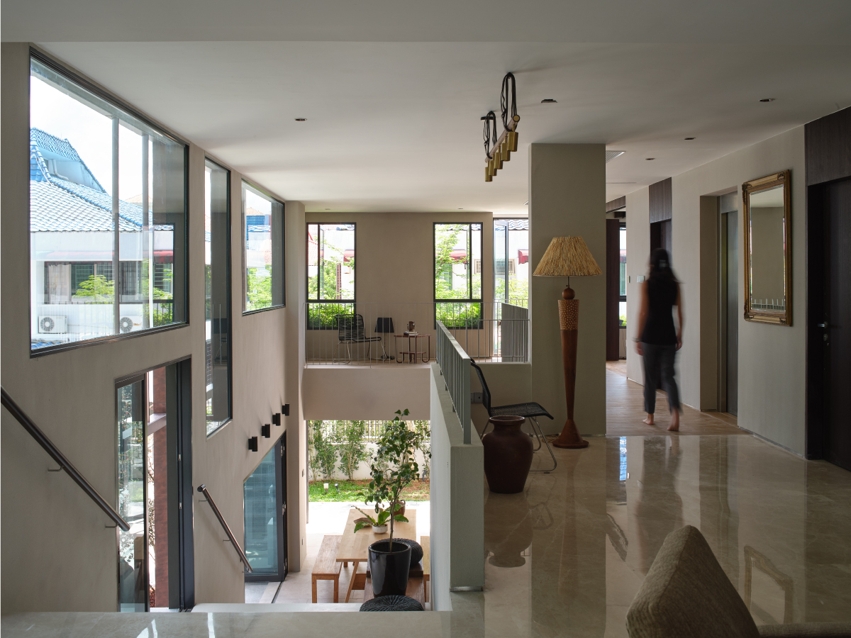 Double-volume interior with tall windows looking onto neighbouring rooftops and a marble floor catching the light