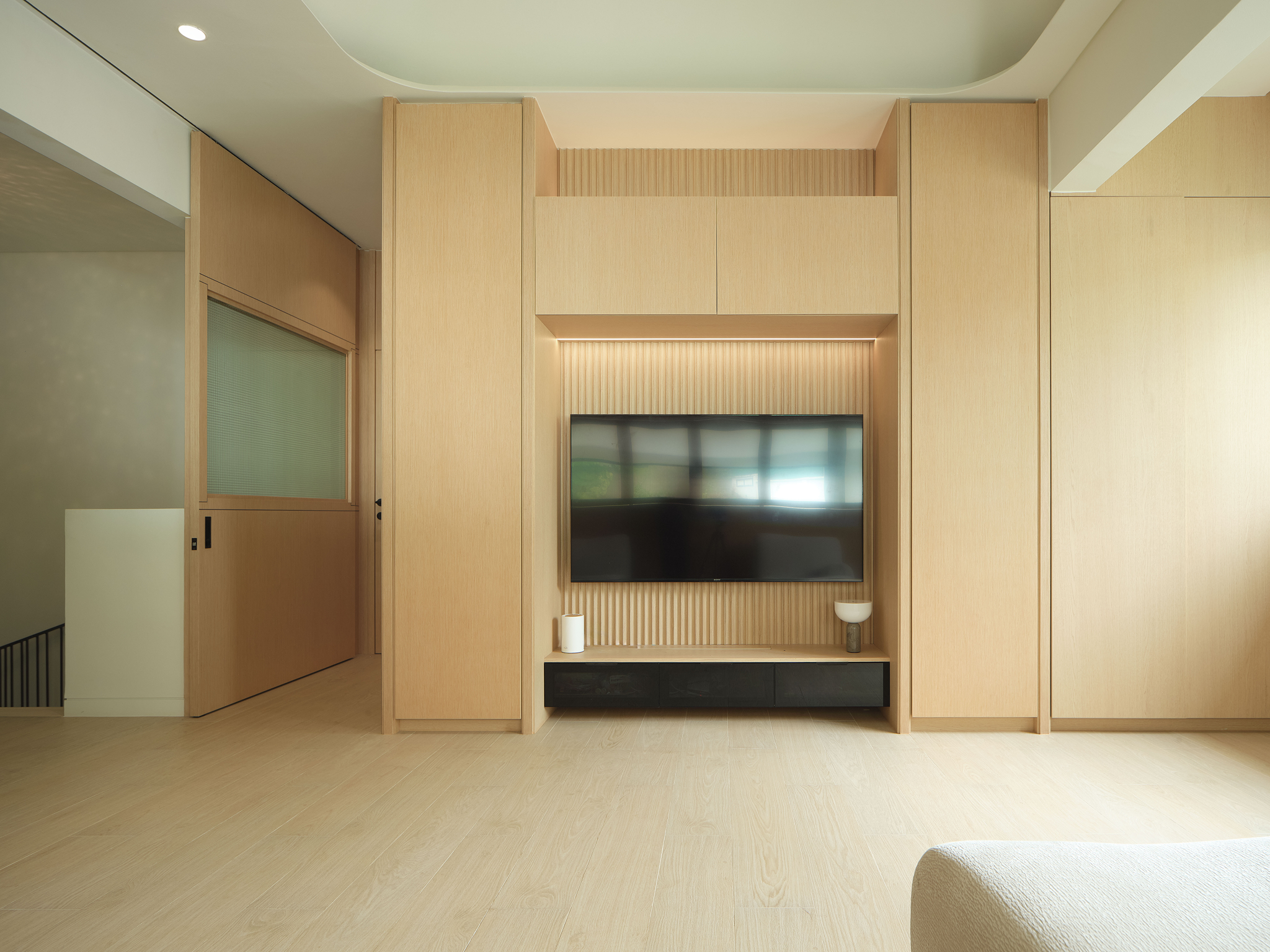 Bedroom with a fluted timber media wall and pale oak flooring